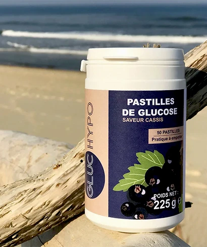 boite de pastilles de glucose saveur cassis gluc hypo 50 pastilles 225g posée sur un bois flotté à la plage